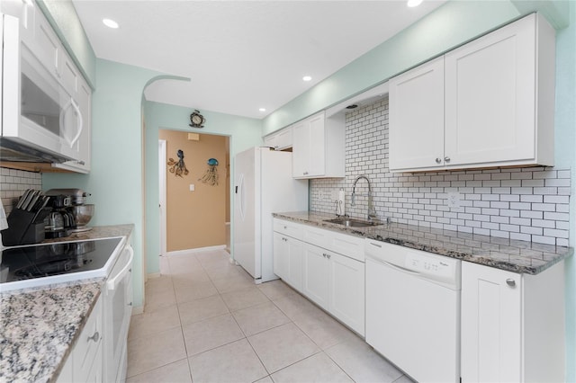 kitchen with sink, tasteful backsplash, stone countertops, white appliances, and white cabinets