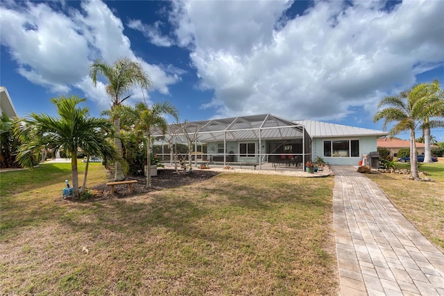 back of house featuring a lawn and glass enclosure