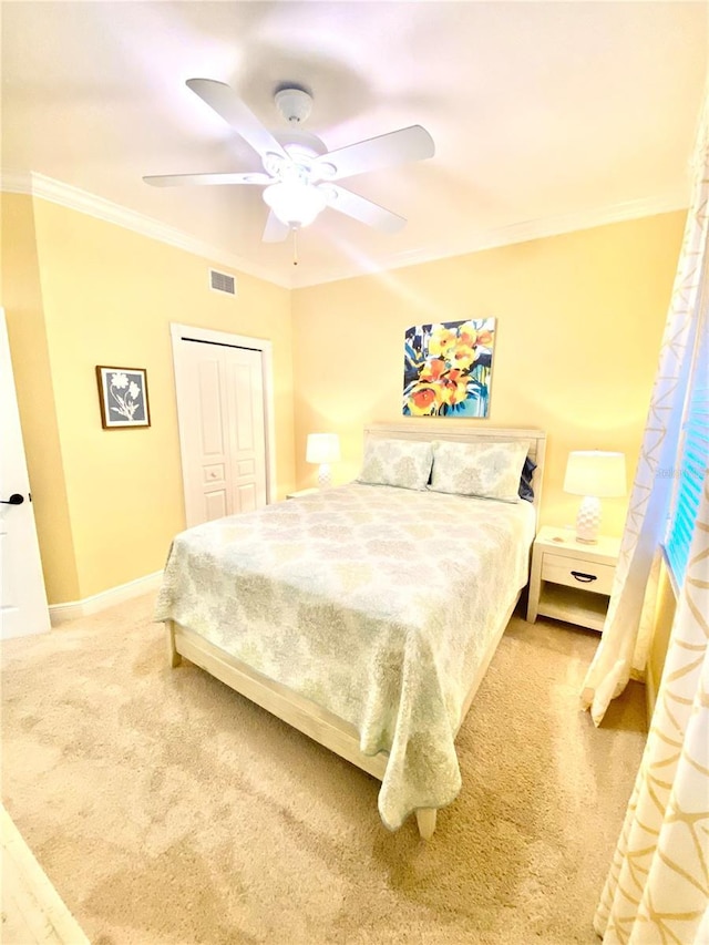 bedroom with ornamental molding, carpet, ceiling fan, and a closet