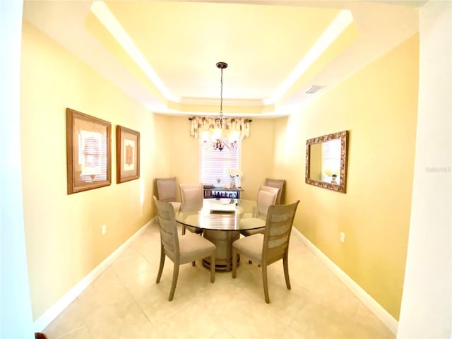 tiled dining room with an inviting chandelier and a raised ceiling