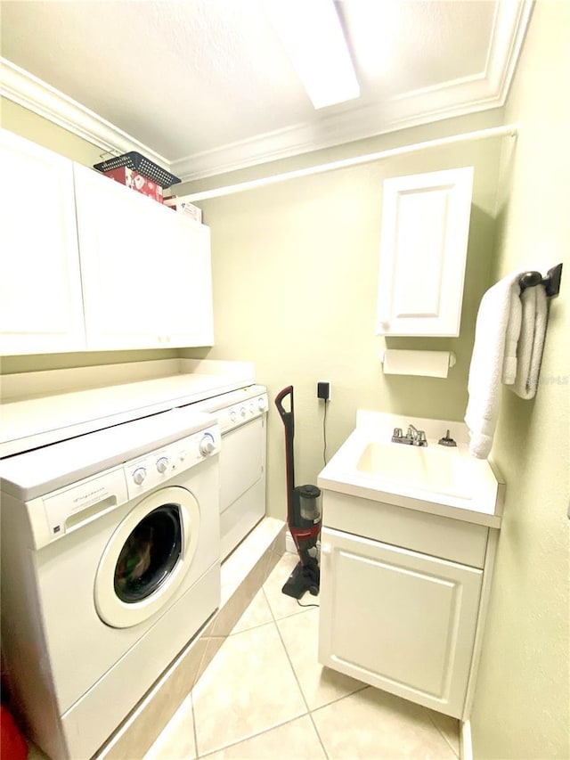 clothes washing area with sink, cabinets, light tile patterned floors, ornamental molding, and washing machine and dryer