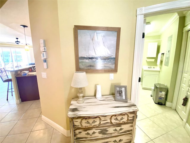 hall with crown molding, light tile patterned floors, baseboards, and a sink