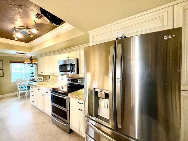 kitchen featuring hanging light fixtures, stainless steel appliances, a notable chandelier, a tray ceiling, and light tile patterned flooring