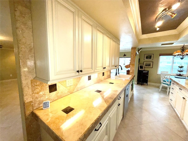 kitchen with a tray ceiling, backsplash, light stone countertops, and sink