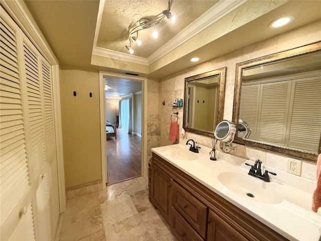 bathroom with a textured ceiling, vanity, crown molding, and a tray ceiling