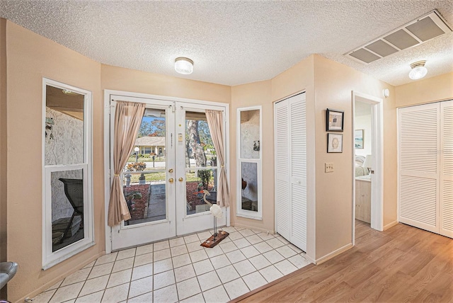 doorway with a textured ceiling and light wood-type flooring