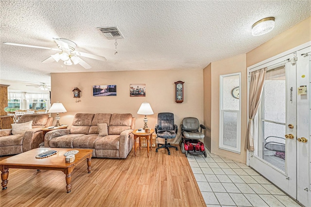 living room with french doors, a textured ceiling, light wood-type flooring, and ceiling fan