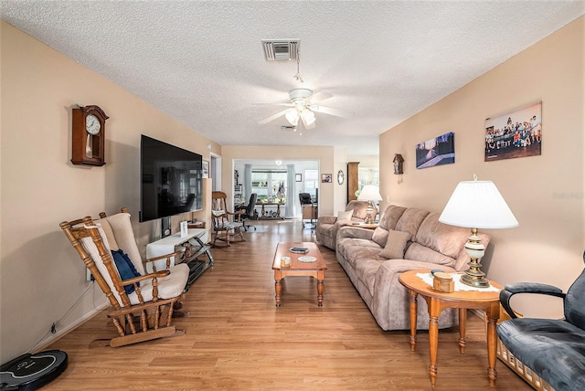 living room featuring ceiling fan, a textured ceiling, and light hardwood / wood-style flooring