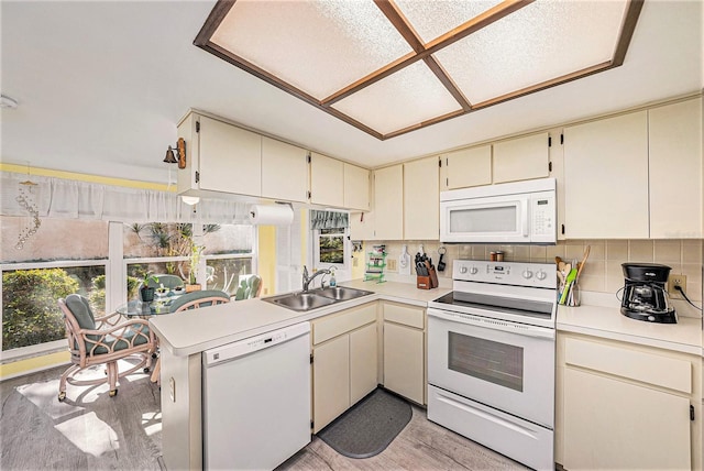 kitchen featuring kitchen peninsula, sink, white appliances, and cream cabinetry