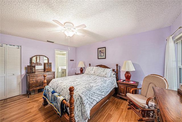 bedroom featuring ensuite bath, a textured ceiling, ceiling fan, light hardwood / wood-style floors, and a closet