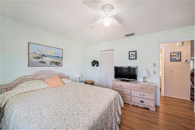 bedroom featuring a textured ceiling, a closet, ceiling fan, and hardwood / wood-style flooring