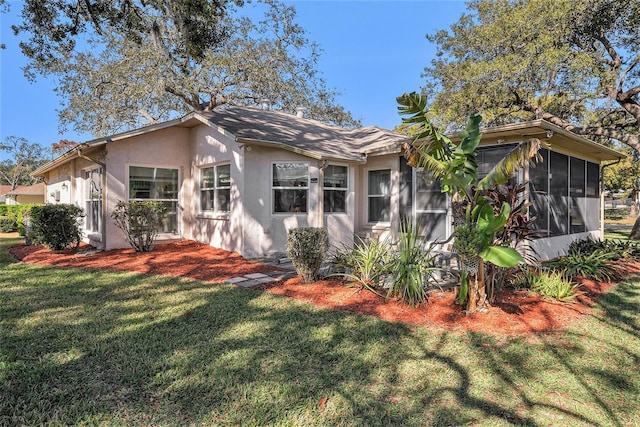 back of house featuring a lawn and a sunroom