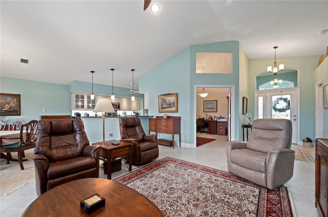 tiled living room with high vaulted ceiling and a notable chandelier