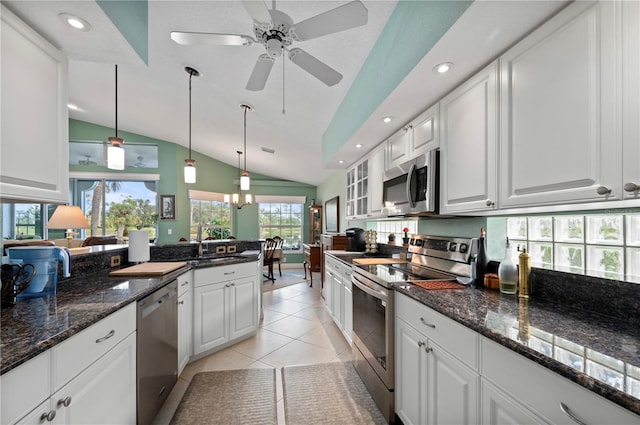 kitchen with stainless steel appliances, light tile patterned floors, decorative light fixtures, white cabinetry, and lofted ceiling