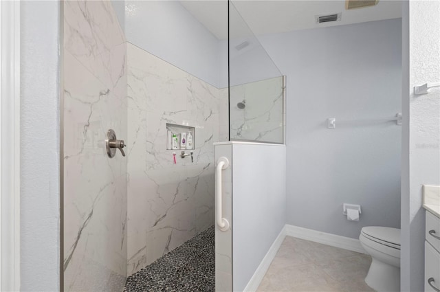 bathroom with tile patterned flooring, vanity, toilet, and tiled shower