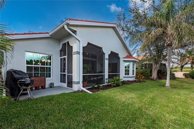 rear view of property with a sunroom, a patio, and a lawn