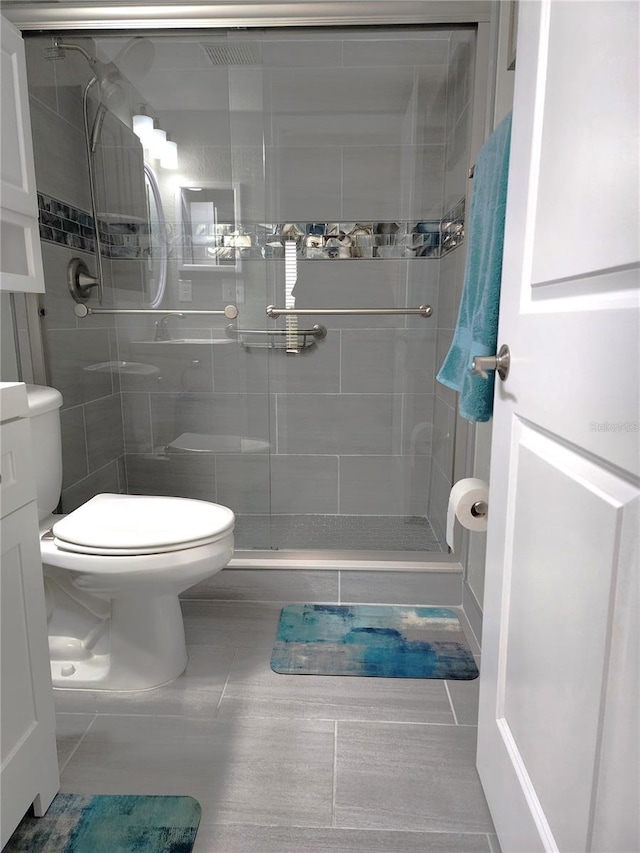 bathroom featuring vanity, a tile shower, tile patterned floors, and toilet