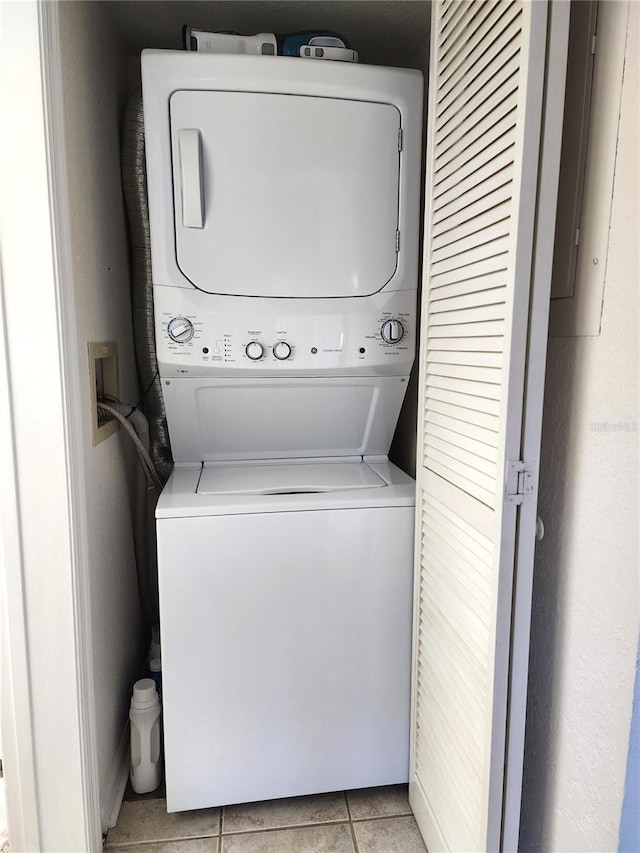 laundry area featuring stacked washer and clothes dryer and light tile patterned floors