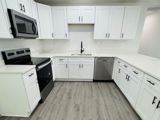 kitchen with sink, white cabinets, stainless steel appliances, and light hardwood / wood-style flooring