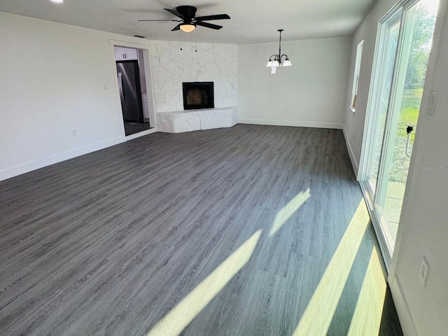 unfurnished living room with a fireplace, ceiling fan with notable chandelier, and dark hardwood / wood-style floors