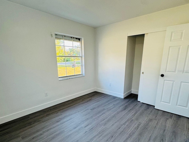 unfurnished bedroom with dark hardwood / wood-style floors and a closet