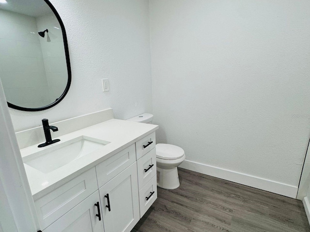 bathroom featuring wood-type flooring, vanity, toilet, and walk in shower