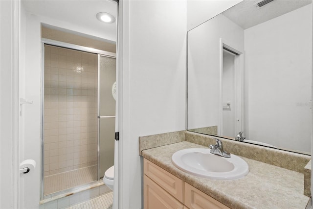 bathroom featuring toilet, tile patterned floors, walk in shower, and vanity