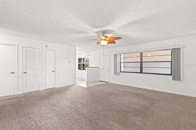 unfurnished living room featuring ceiling fan, a textured ceiling, and carpet flooring