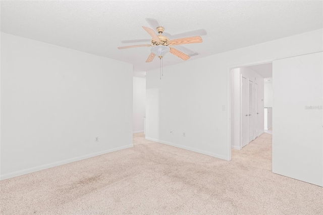 empty room featuring a textured ceiling, ceiling fan, and light carpet