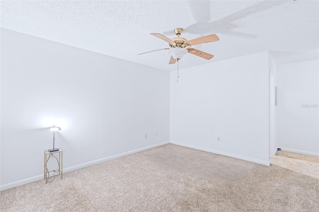 carpeted spare room featuring a ceiling fan, a textured ceiling, and baseboards