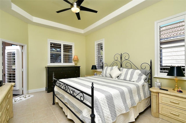 tiled bedroom featuring a tray ceiling and ceiling fan