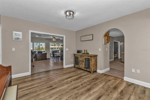 interior space featuring arched walkways, baseboards, and wood finished floors