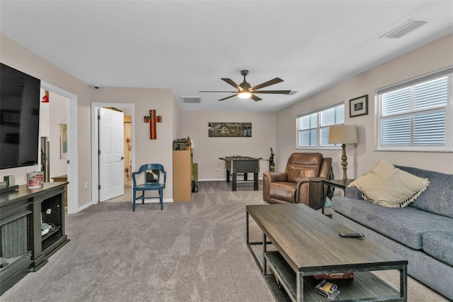 living area with visible vents, carpet floors, baseboards, and a ceiling fan