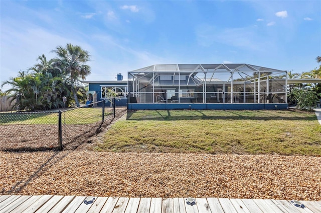 rear view of property with a lanai, a lawn, and fence