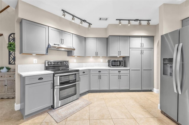 kitchen featuring under cabinet range hood, stainless steel appliances, and gray cabinetry