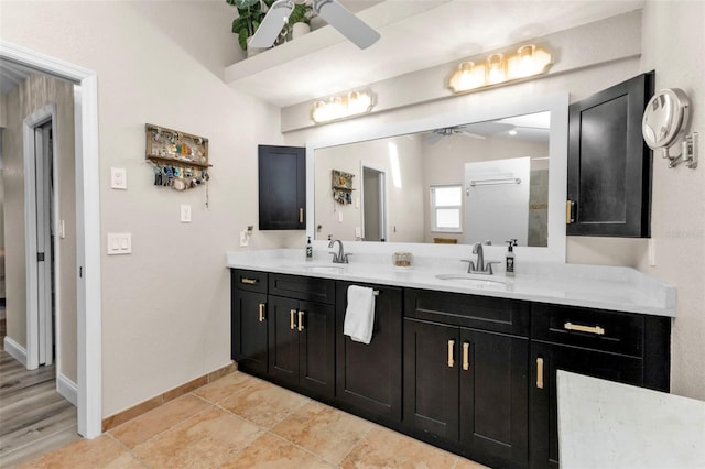 bathroom with a sink, baseboards, ceiling fan, and double vanity