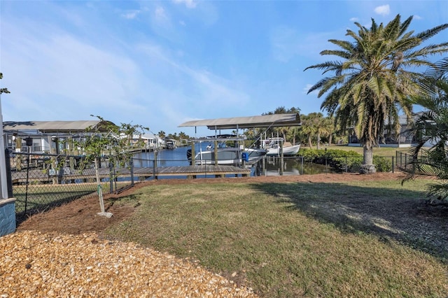 view of dock with a yard, a water view, boat lift, and fence