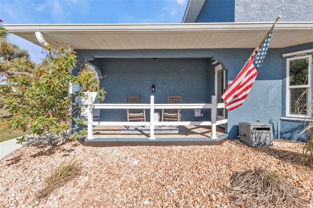 view of exterior entry featuring cooling unit and stucco siding