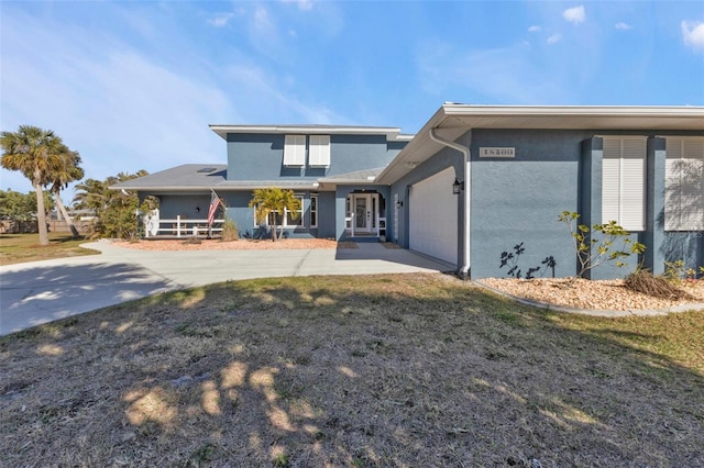 back of property with stucco siding, concrete driveway, a lawn, and a garage