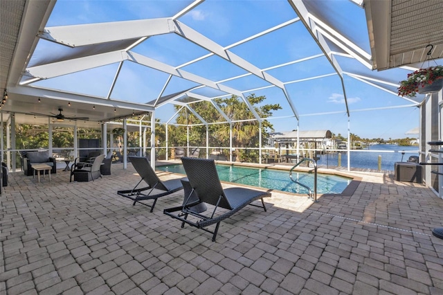 pool with a ceiling fan, a lanai, a patio area, and a water view