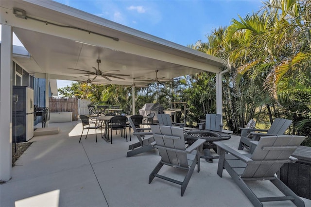 view of patio with outdoor dining space, ceiling fan, fence, and an outdoor fire pit