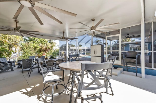 view of patio featuring a lanai, outdoor dining area, and a ceiling fan