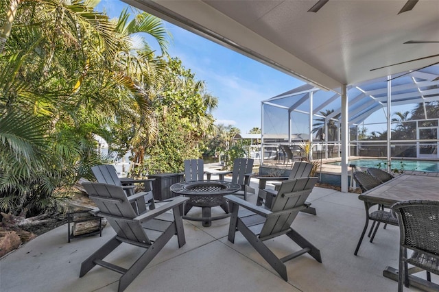 view of patio / terrace with an outdoor pool, glass enclosure, and a fire pit