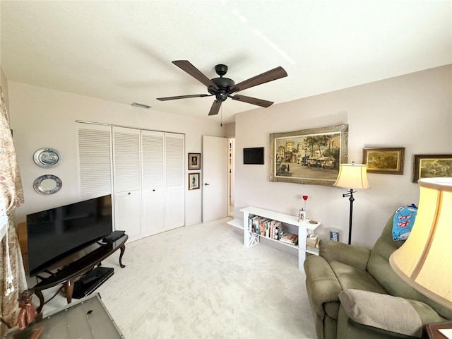 living area with ceiling fan and carpet