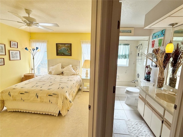 bedroom featuring sink, ceiling fan, connected bathroom, and a textured ceiling