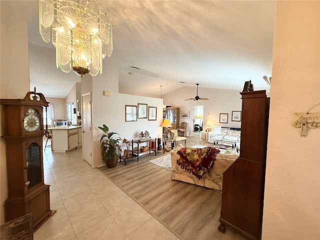 tiled living room with ceiling fan with notable chandelier, a healthy amount of sunlight, and vaulted ceiling