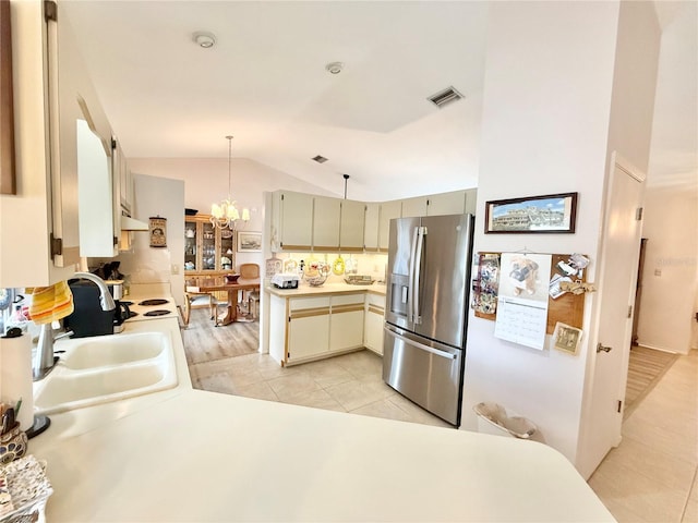 kitchen with lofted ceiling, stainless steel refrigerator with ice dispenser, hanging light fixtures, light tile patterned flooring, and cream cabinetry