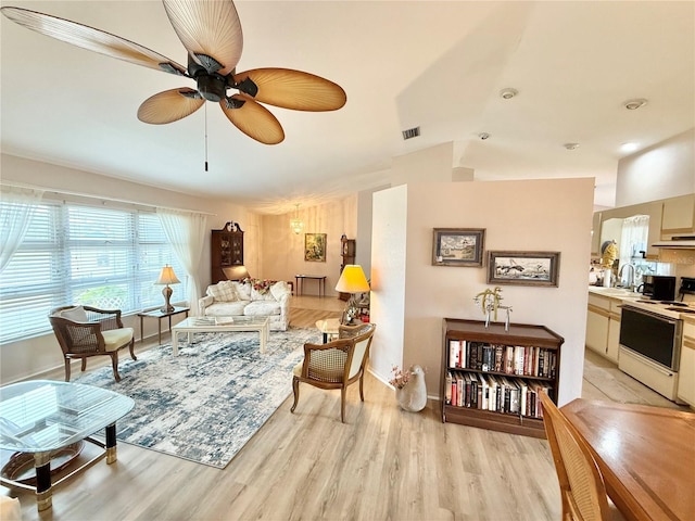 living room featuring sink, light hardwood / wood-style flooring, lofted ceiling, and ceiling fan