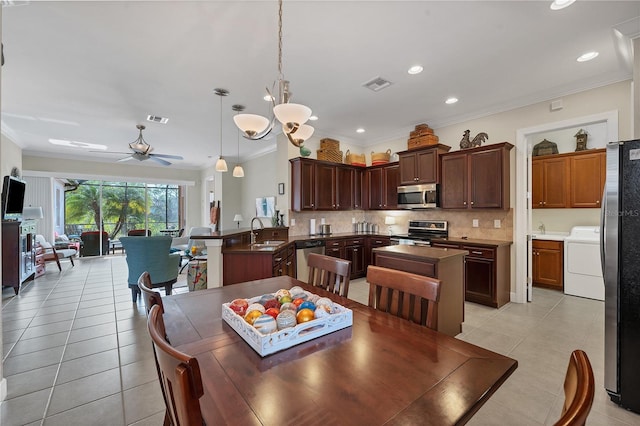 dining room featuring washer / clothes dryer, crown molding, sink, and ceiling fan with notable chandelier