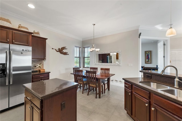 kitchen with pendant lighting, sink, stainless steel fridge, ornamental molding, and a kitchen island